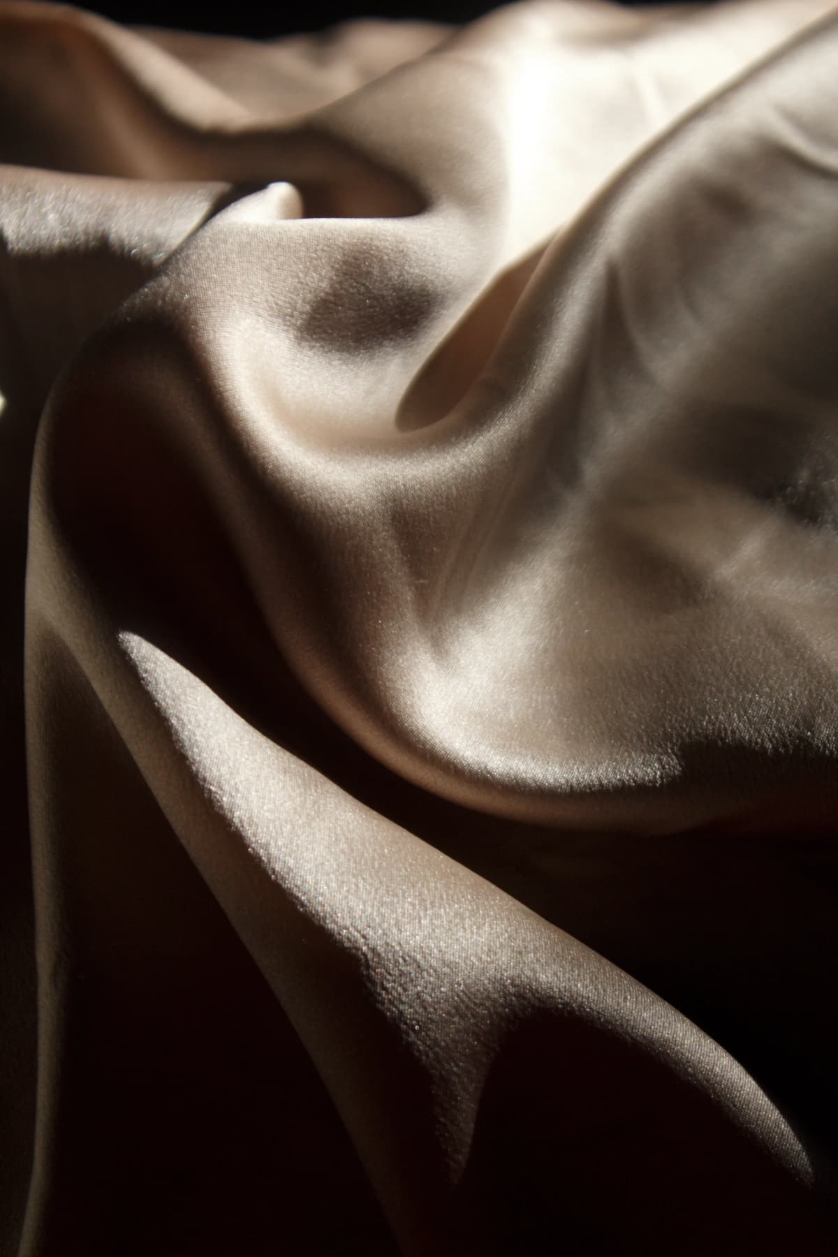 Draped champagne silk fabric with soft flowing folds in warm, dramatic lighting