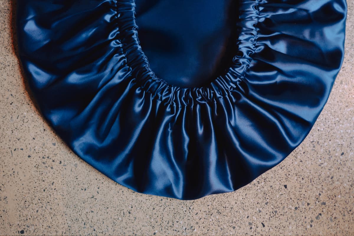 Navy silk Max Volume bonnet laid flat, showing its oversized gathered elasticated edge and generous internal room.