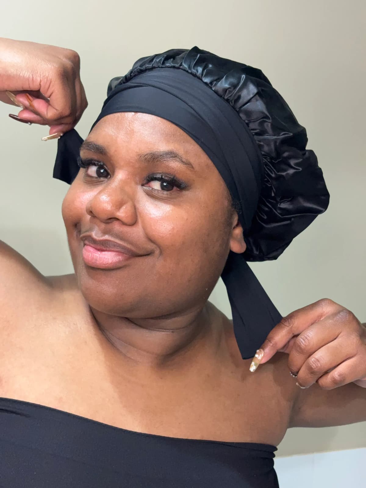 Person wearing a black silk bonnet with a wide black head-wrap tied at the back, indoors.