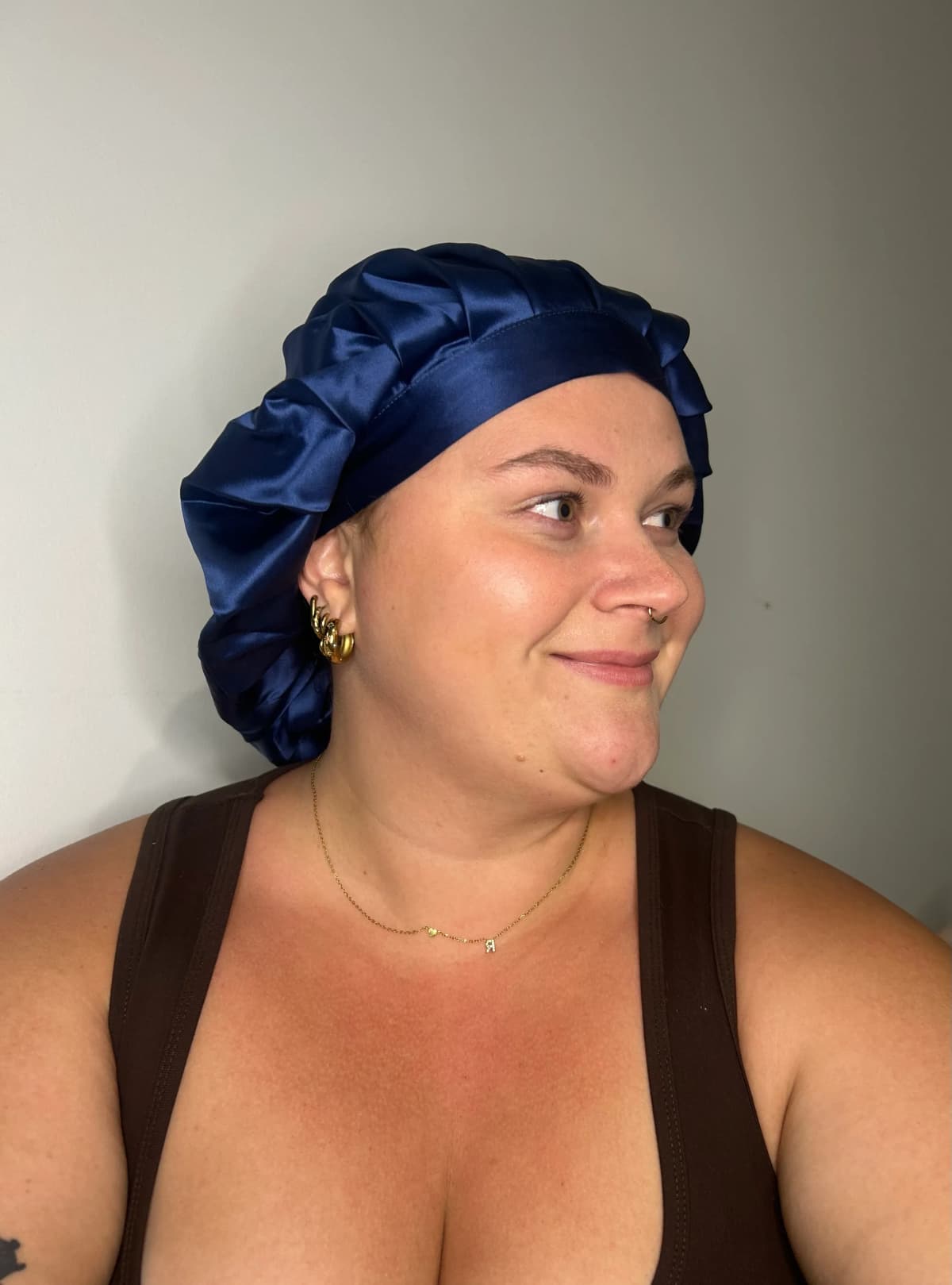 Customer smiling and looking to the side while wearing the navy Kova Silk All Rounder bonnet.