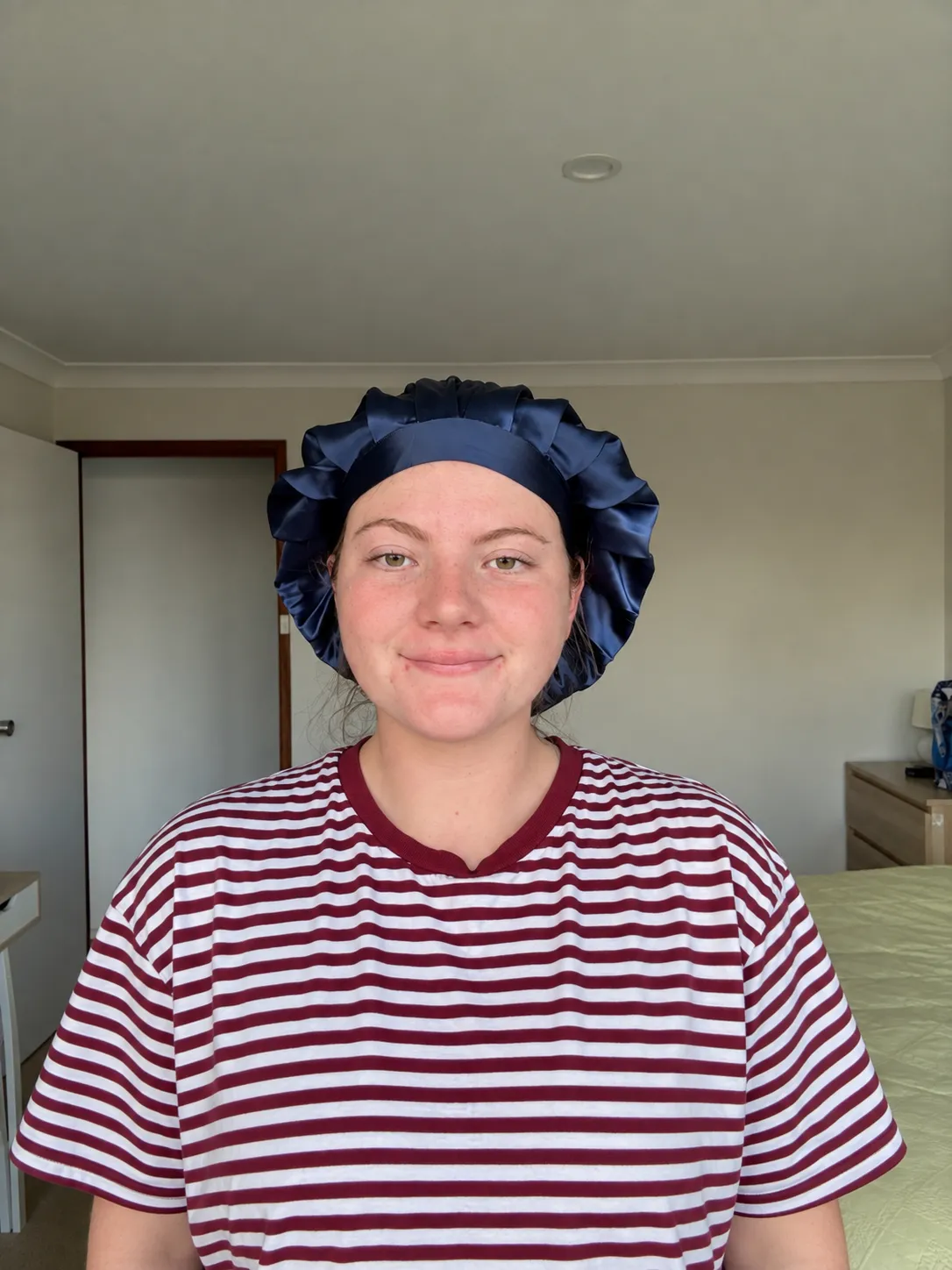 Front view of a customer wearing the navy Kova Silk All Rounder bonnet with its satin band.
