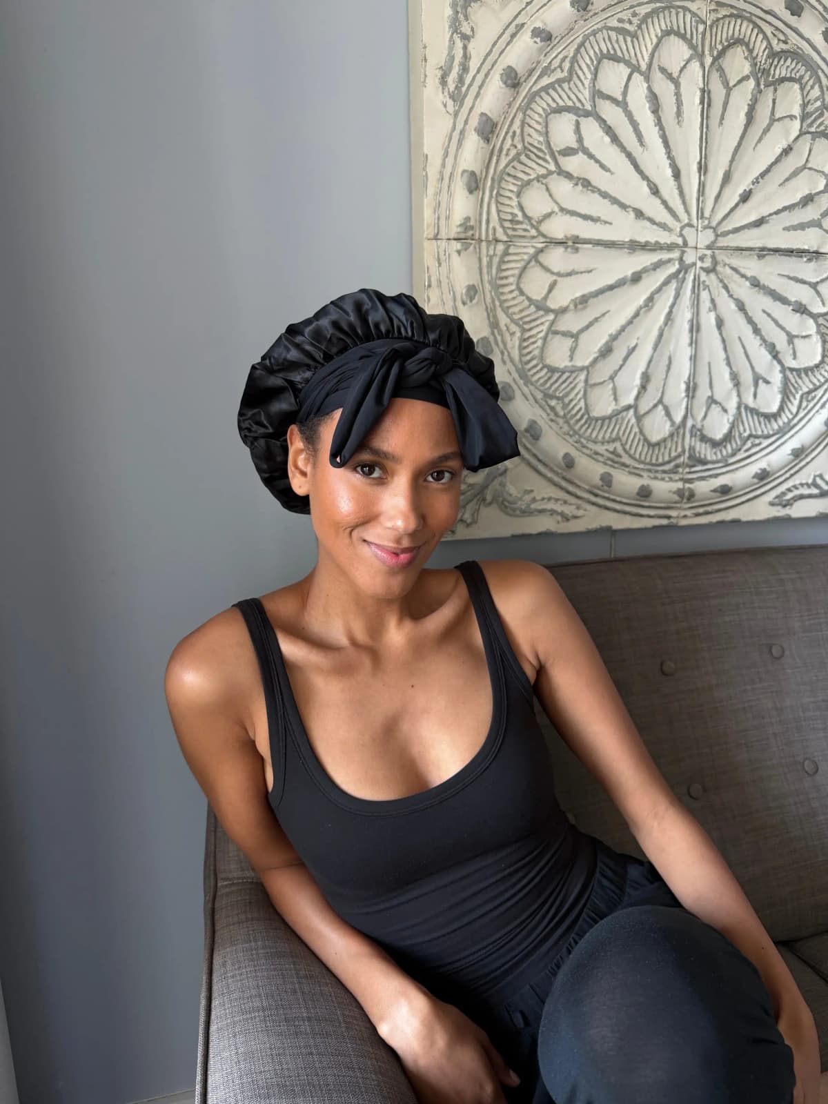 Person wearing a black silk bonnet with a black head-wrap tied in a bow.