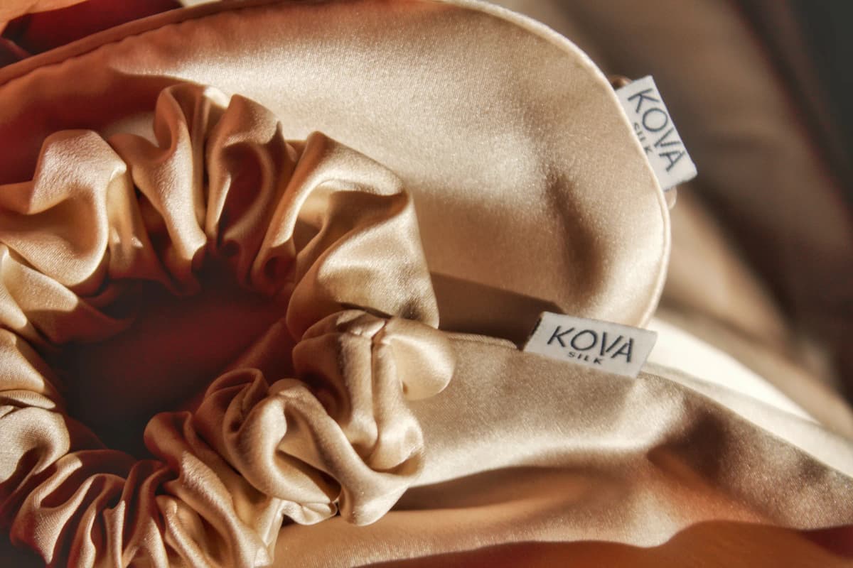 Kova Silk sleep mask and silk scrunchies styled on beige mulberry silk